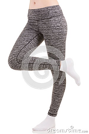 Woman legs from the side in grey sports thermal pants standing on one leg with other leg raised in white socks Stock Photo