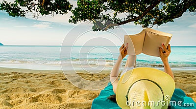 Woman lie down on green towel that put on sand beach under the tree and reading a book. Slow life on summer vacation. Asian woman Stock Photo