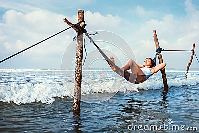 Woman lies in hammock over the waves and enjoy with sun light Stock Photo