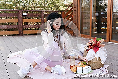 woman in light clothes and white sneakers sits on a plaid Stock Photo