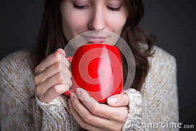 Woman in a light sweater holding a red cup of coffee Stock Photo