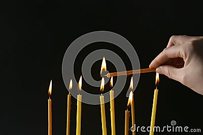 Woman lighting church candle on black background, closeup Stock Photo