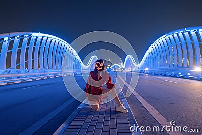 Woman with lighting neon glow mask on Meydan Bridge and street road or path way on highway in Dubai Downtown at night, urban city Stock Photo