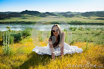 Woman like a fairy on the magic field near the river. Young woman with dandelion. Fantasy style Stock Photo