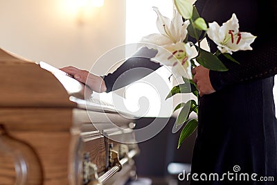 Woman with lily flowers and coffin at funeral Stock Photo