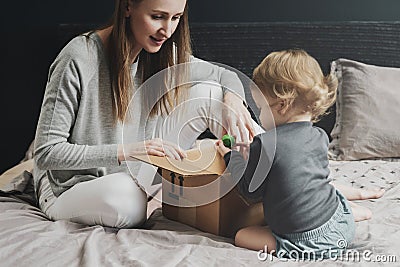 Woman and little child playing with big cardboard box. Mother putting things into package Stock Photo