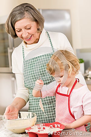Woman and little girl baking cupcakes together Stock Photo