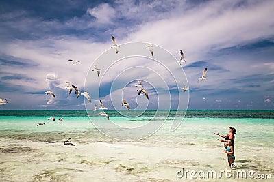 Woman and little girl enjoying their leisure time on the beach, feeding flying seagulls Editorial Stock Photo