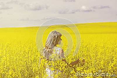 Woman with long hair back view, yellow rapeseed canola field enjoying nature and sunlight. Stock Photo