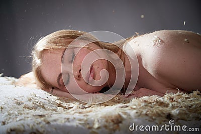 Woman with long hair relaxing. Sweet dreams concept. Girl on calm face covered with feathers and fluff. Model posing in Stock Photo