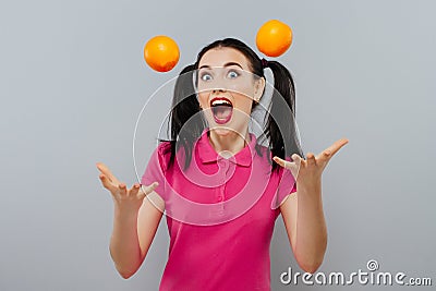 Woman with long straight hair, holding two oranges, looking up Stock Photo