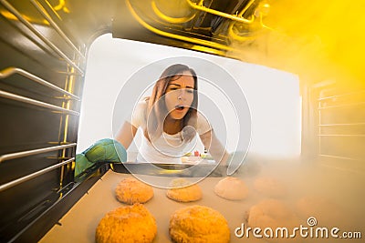 Woman Looking At Burnt Cookies In Oven Stock Photo