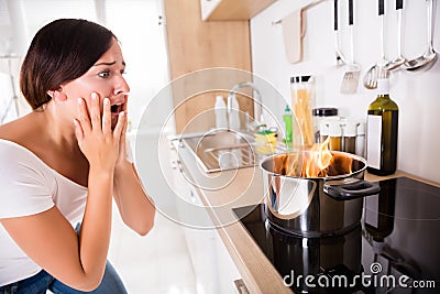 Woman Looking At Burnt Food In Cooking Pot Stock Photo