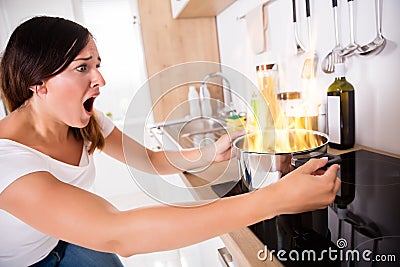 Woman Looking At Burnt Food In Cooking Pot Stock Photo