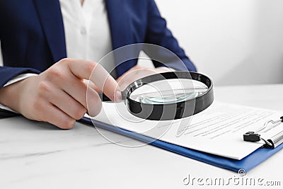 Woman looking at document through magnifier at white marble table, closeup. Searching concept Stock Photo