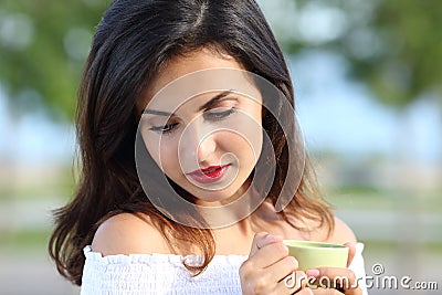 Woman looking down holding a coffee cup outdoors Stock Photo