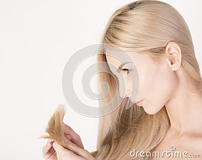 Woman looking at ends of her long blonde hair. Stock Photo