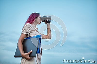Woman looking forward in binoculars. Lady holding laptop and folder. Goal setting and new horizons concept, copy space Stock Photo