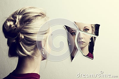 Woman looking at her face in three shards of broken mirror Stock Photo