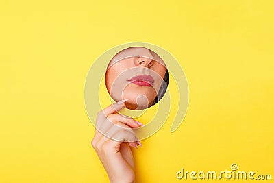 Woman looking in the hole, bright beautiful makeup, big eyes and lips, bright lipstick, professional cosmetics and facial care. Stock Photo