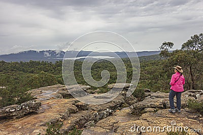 A woman looking at incoming storm on sandstone cliff of Reeds Lookout in Grampians National Park, Victoria, Australia. Editorial Stock Photo