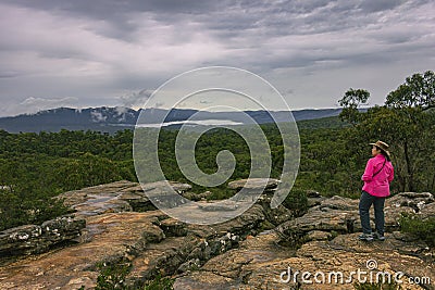 A woman looking at incoming storm on sandstone cliff of Reeds Lookout in Grampians National Park, Victoria, Australia. Editorial Stock Photo