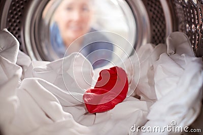 Woman Looking Inside Washing Machine With Red Sock Mixed With White Laundry Stock Photo