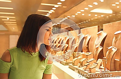 Woman looking at jewelry in store window. Girl chooses silver, gold, diamonds, precious stones Stock Photo