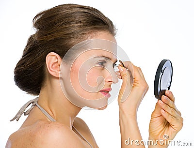 Woman looking into mirrorand using tweezers Stock Photo