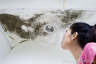 Woman looking at the roof damage Stock Photo