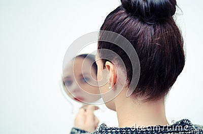 Woman looking at self reflection in mirror Stock Photo