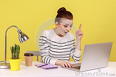Woman looking surprised by genius idea, raising finger up inspired while working on laptop. Stock Photo