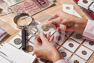 Woman looks at the collector s coin Stock Photo