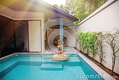 A woman lounging in a tropical villa swimming pool Stock Photo