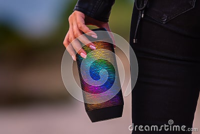 Woman loves to listen music with portable LED multicolour wireless bluetooth speakers. Enjoying the music outdoors. Stock Photo