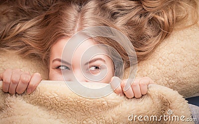 Woman lying in bed under blanket Stock Photo