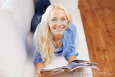 Woman lying on couch and reading magazine at home Stock Photo