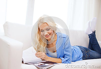 Woman lying on couch and reading magazine at home Stock Photo