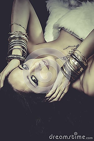 Woman lying and sensual with bracelets of gold and silver, green Stock Photo