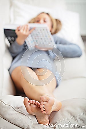 Woman lying on sofa with book Stock Photo