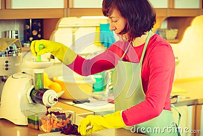 Woman make vegetables juice in juicer machine Stock Photo