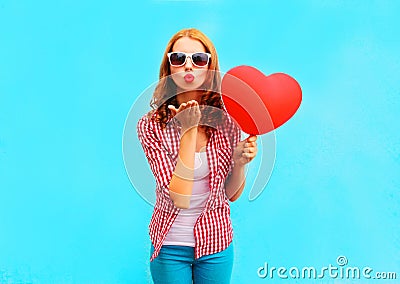 Woman makes an air kiss with a red balloon in the shape of a heart Stock Photo