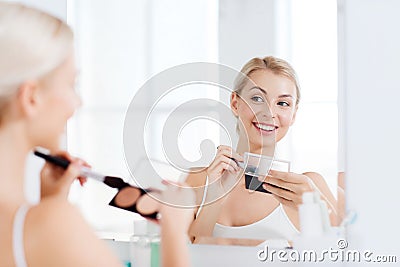 Woman with makeup brush and foundation at bathroom Stock Photo