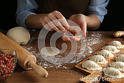 Woman making gyoza at wooden table, closeup Stock Photo