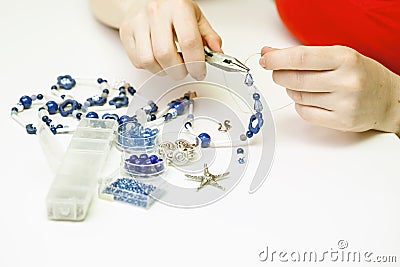 Woman making necklase from colorful plastic beads on light background Stock Photo