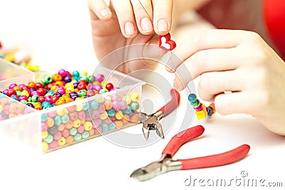 Woman making necklase from colorful plastic beads on light background Stock Photo