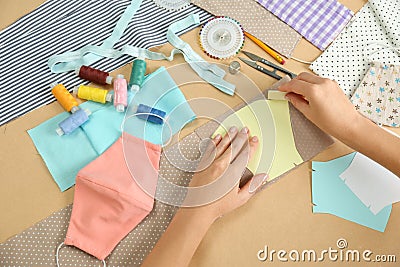 Woman making sewing template for cloth mask at table, closeup. Personal protective equipment during COVID-19 pandemic Stock Photo