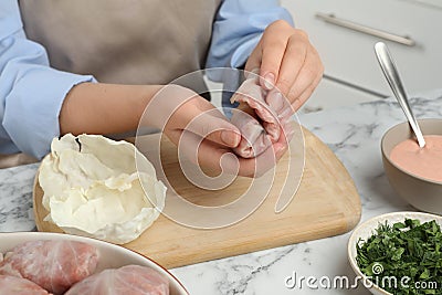 Woman making stuffed cabbage rolls at white marble table, closeup Stock Photo