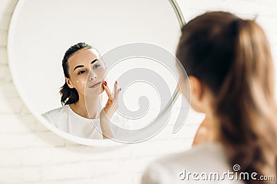 The woman is making up in the bathroom. Woman in bathroom applying cream on face Stock Photo