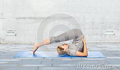 Woman making yoga in plow pose on mat outdoors Stock Photo